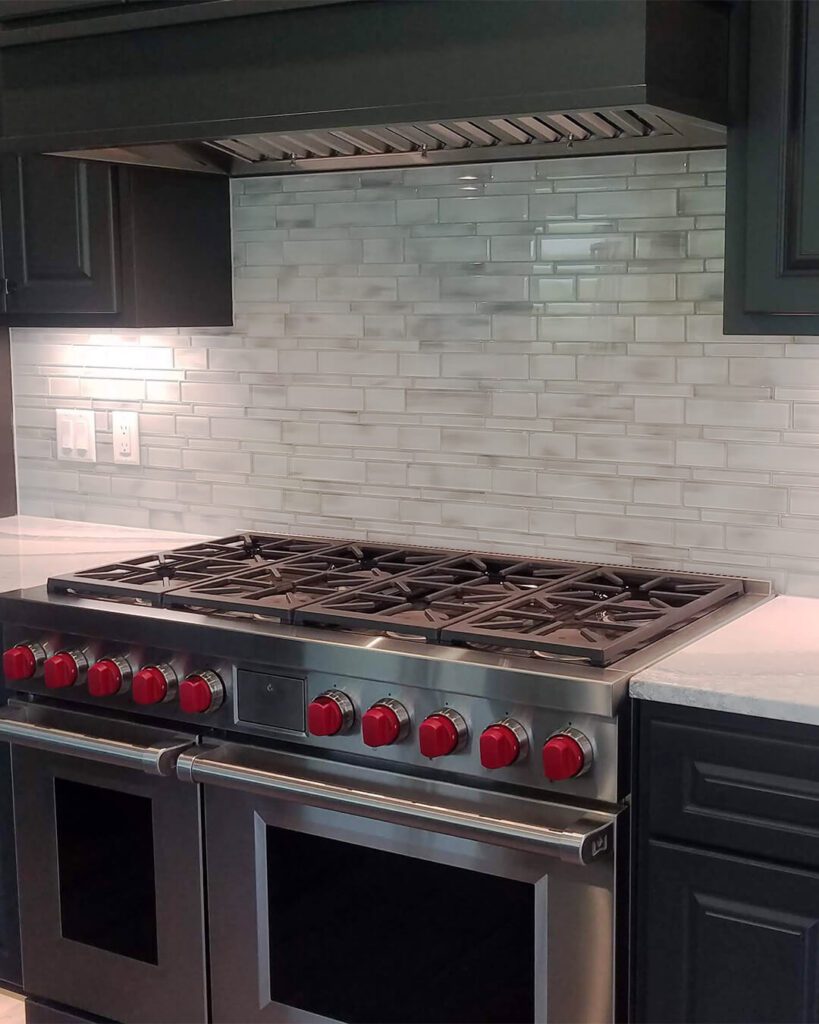 Classic white running bond backsplash in a soft marble look, complementing a professional-grade range—ideal for farmhouse or transitional kitchens with upscale touches.