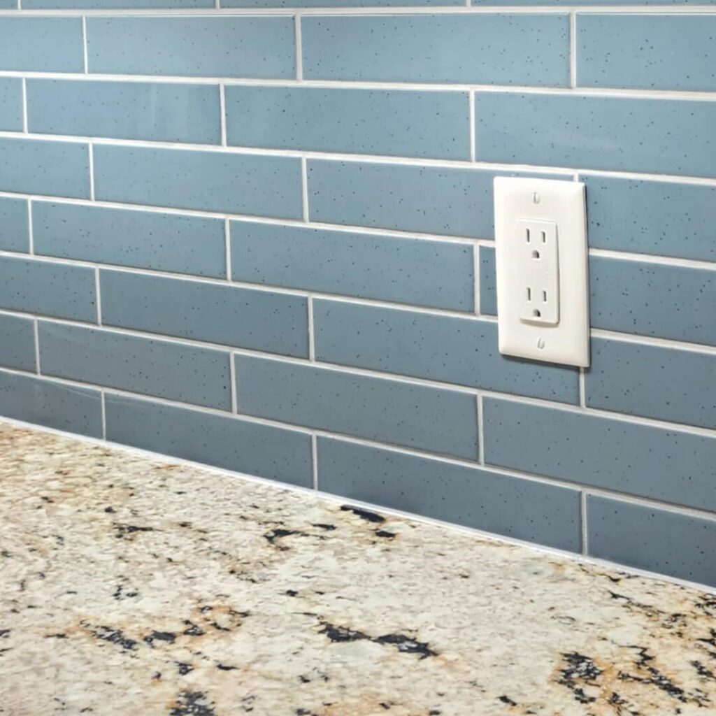 Matte blue running bond backsplash in elongated subway tiles, adding a soft pop of color and timeless charm above granite countertops.